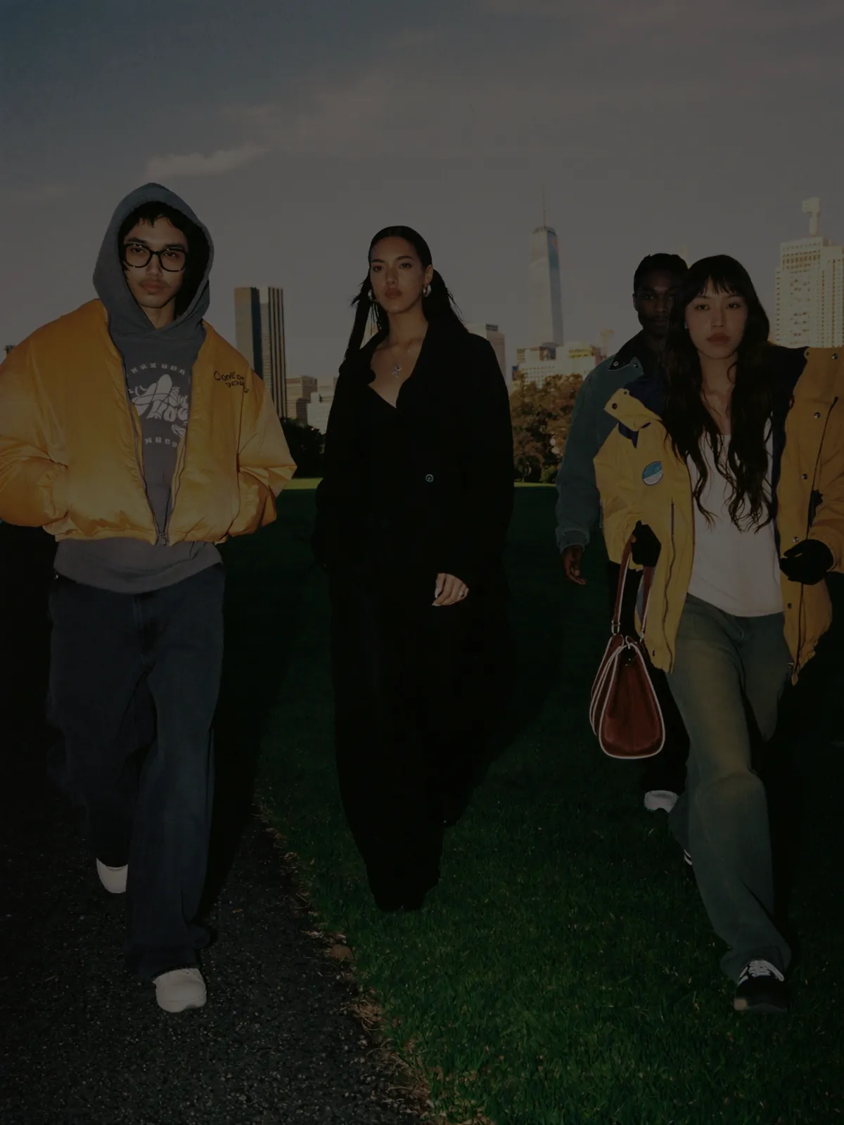 Gruppo di ragazzi in abiti streetwear che camminano su un prato al tramonto, mood editoriale per FerryBoat moda Chioggia